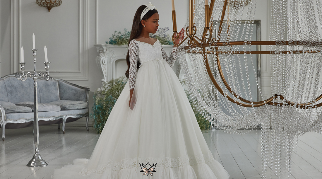 Pretty girl wearing white first holy communion lace dress posing by a crystal chandelier