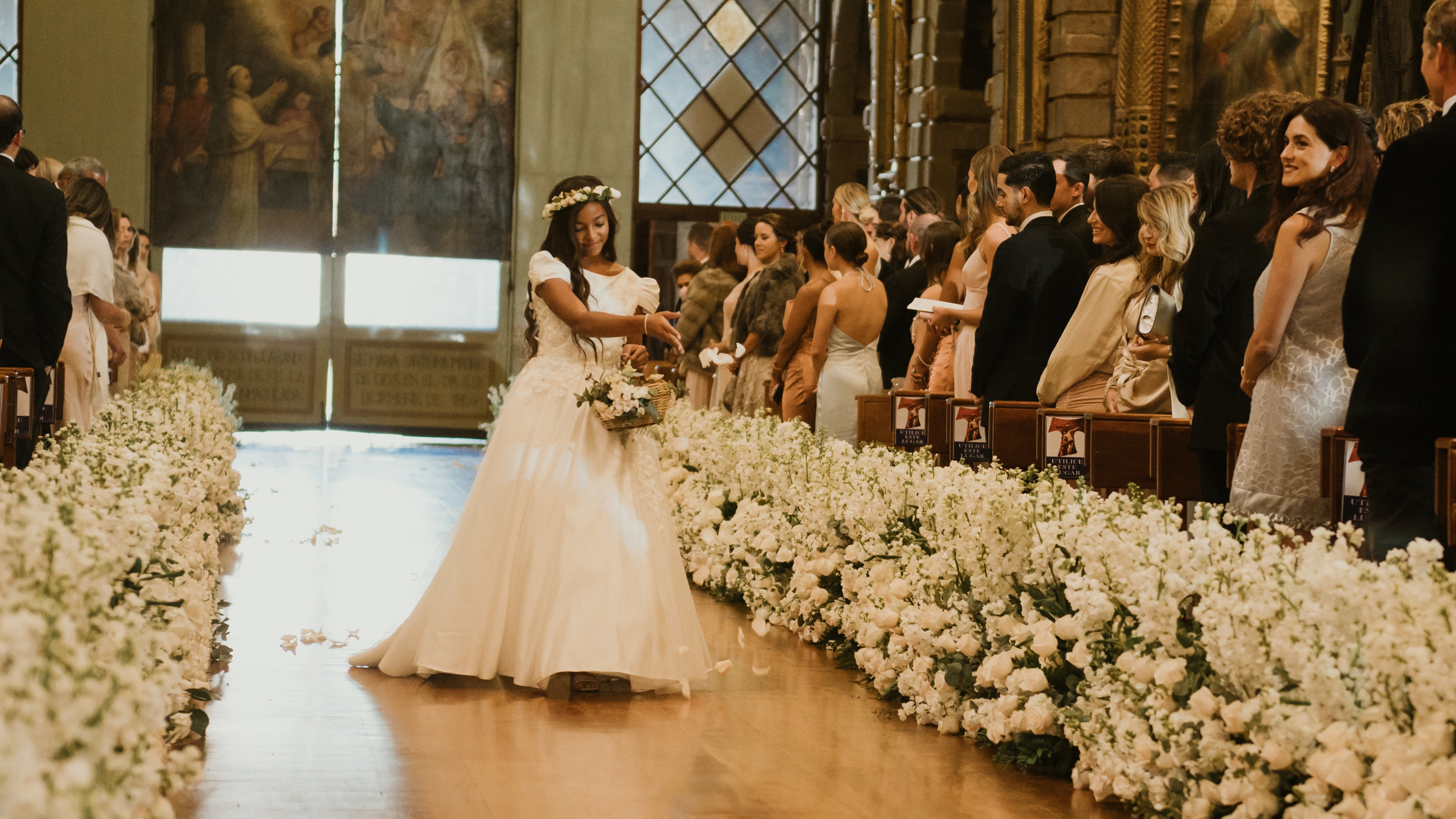 <alt>gorgeous flower girl walking down the isle throwing flower petals wearing a couture ivory dress by miele moda while guests are smiling at her on jasmine tookes wedding in Ecuador</alt>