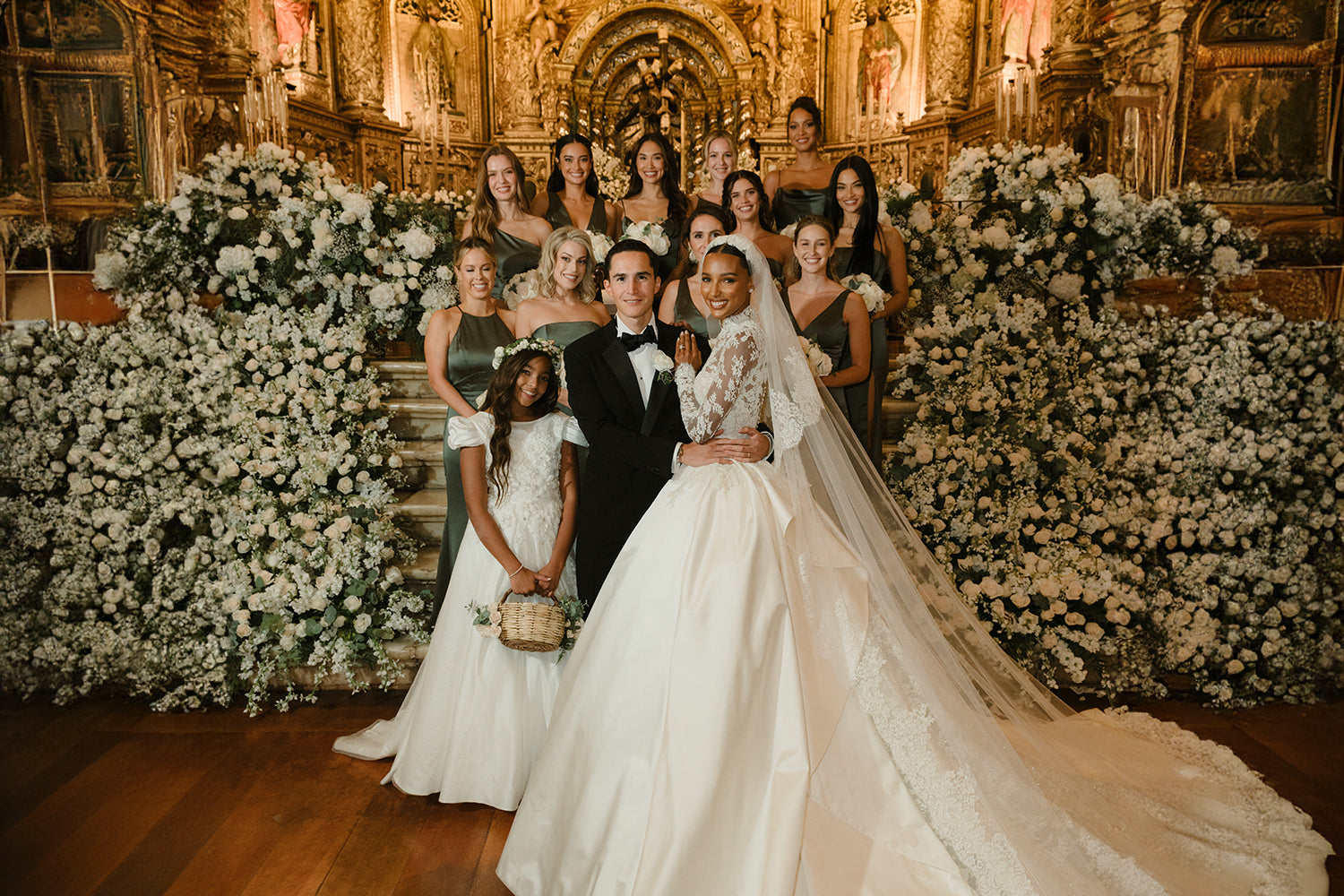 Jasmine Tooks wearing Zuhair Murad wedding gown standing next to her flower girl Chloe wearing Miele Moda gown with her bridal party and husband Juan David Borrero in front of the alter