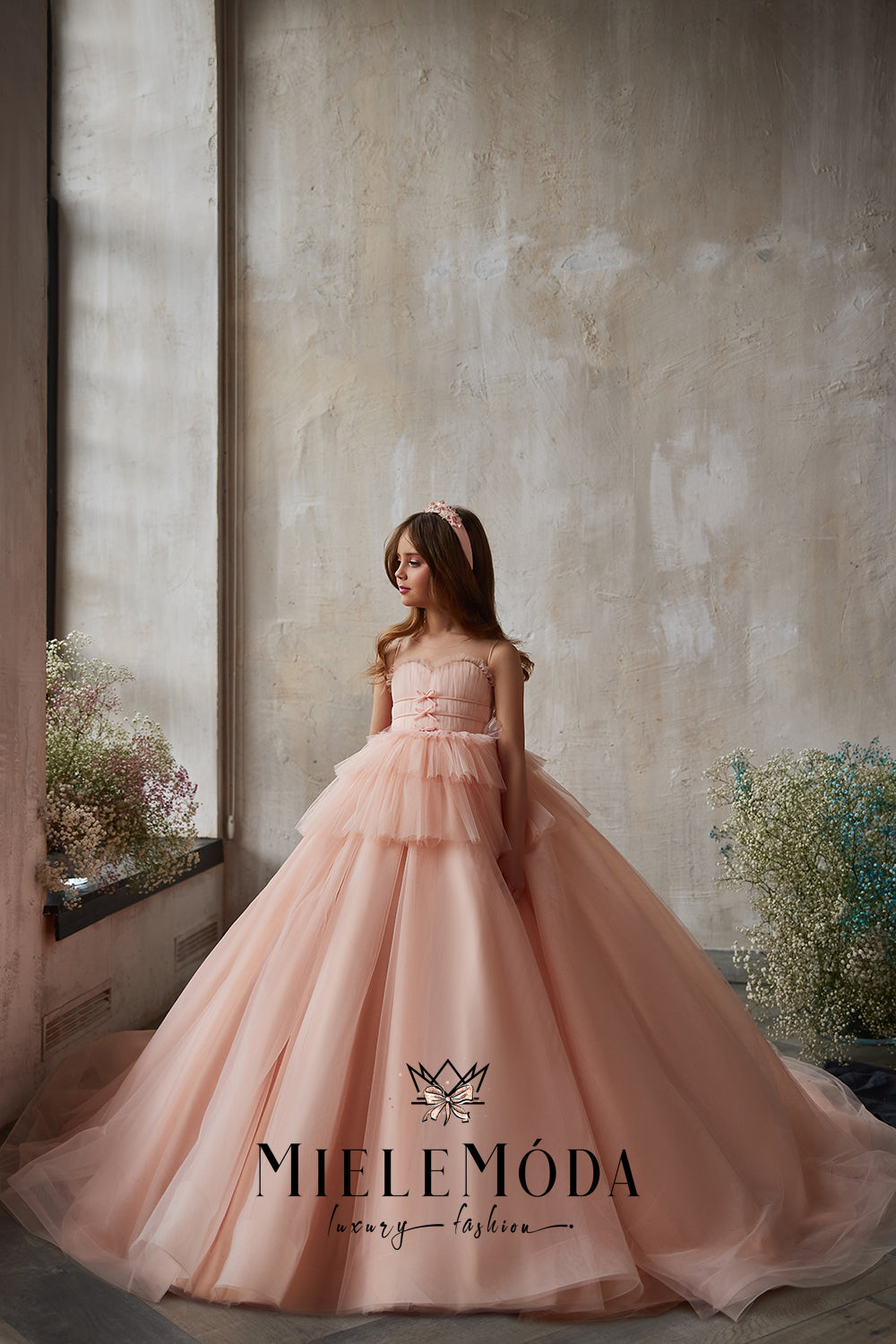 young girl with long dark hair wearing pink ballroom gown modeling for miele moda luxury fashion boutique
