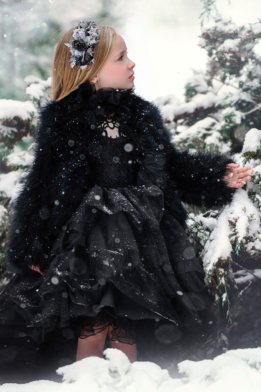 pretty little girl wearing black lace dress in the christmas snow