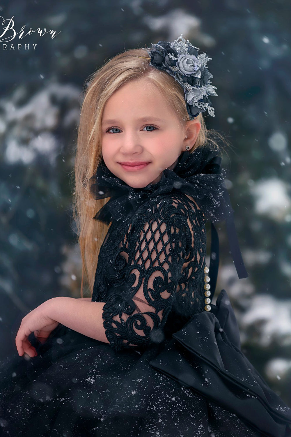 beautiful girl wearing a black lace dress with a huge bow in the snow